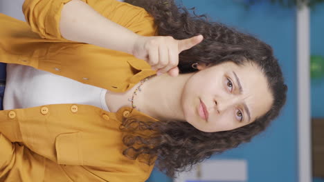 Vertical-video-of-The-young-woman-is-warning-by-looking-at-the-camera.